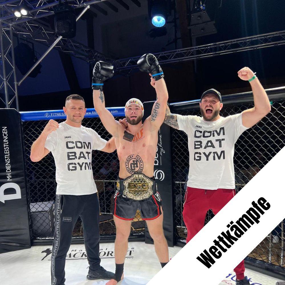 Kämpfer steht mit 2 Trainern im Oktagon und freut sich über den Sieg